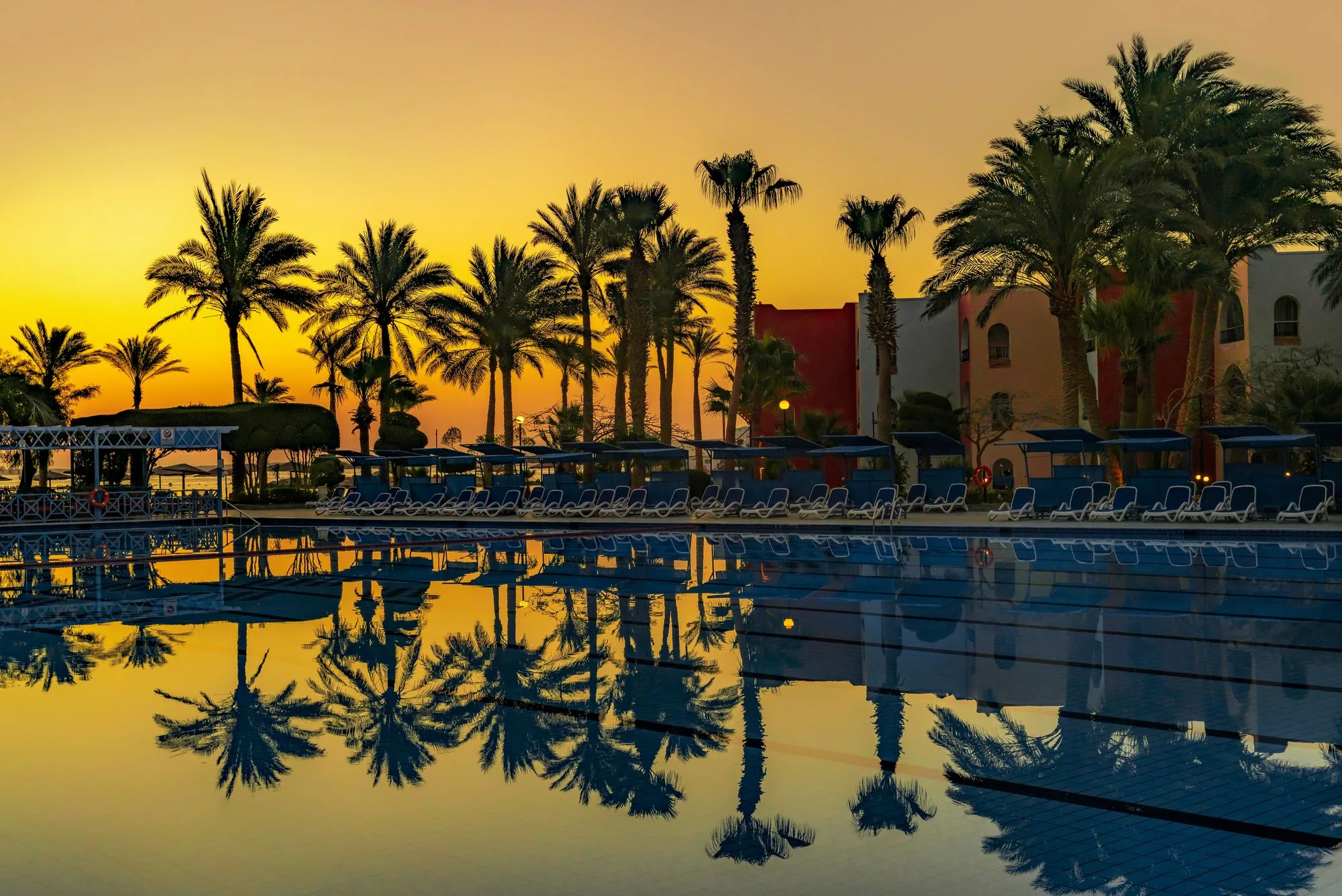 Palmen und ein Resortpool bei Sonnenuntergang